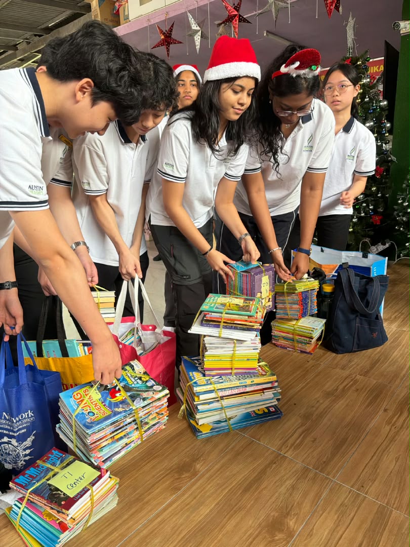 Students in Christmas hats sorting stacks of donated books at Puspanesam Home